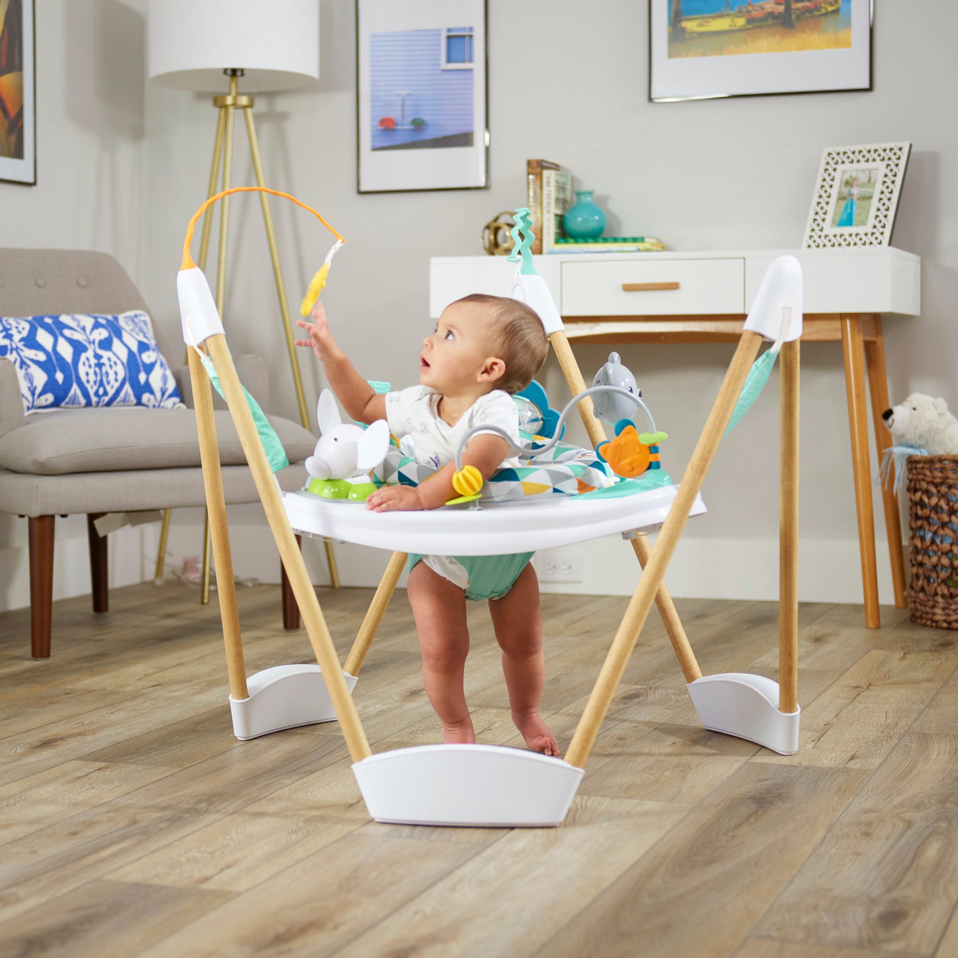 Happy baby playing in a bouncer activity center with a geometric pattern.