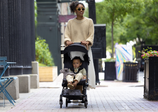 You are a stylish parent, strolling confidently with your happy child in a sleek stroller.