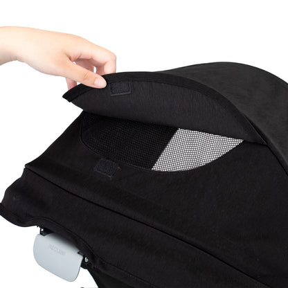 Black baby car seat with a hand adjusting the canopy on a white background