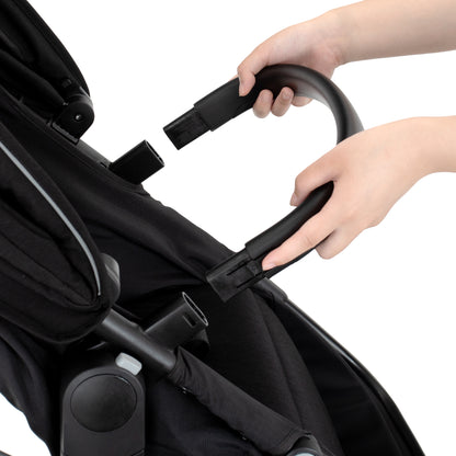 Person adjusting the handle of a black stroller on a white background