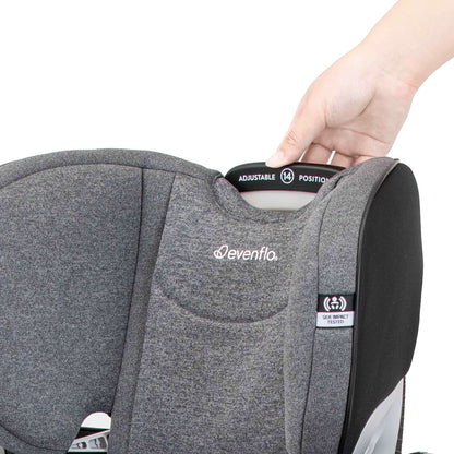 Hand adjusting the 14-position headrest on a gray Evenflo car seat.